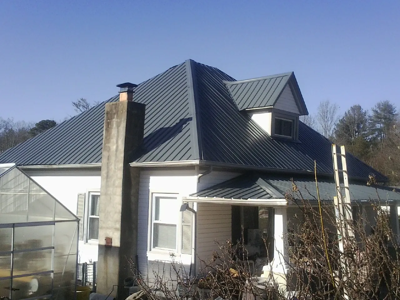 Dark blue standing seam metal roof on a white farmhouse with dormer — Slate & Tile Roof Repair by Roofing Brothers in Trivoli