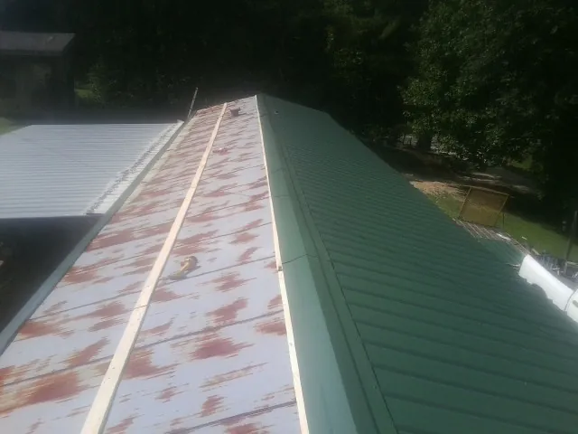 Old rusted panels beside newly installed green metal roofing — Wind Damage Roof Repair by Roofing Brothers in Trivoli