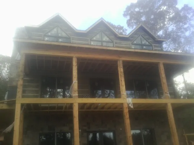 Dormers and porch framing on a large log home under construction — Roof Coating work by our crew in Trivoli