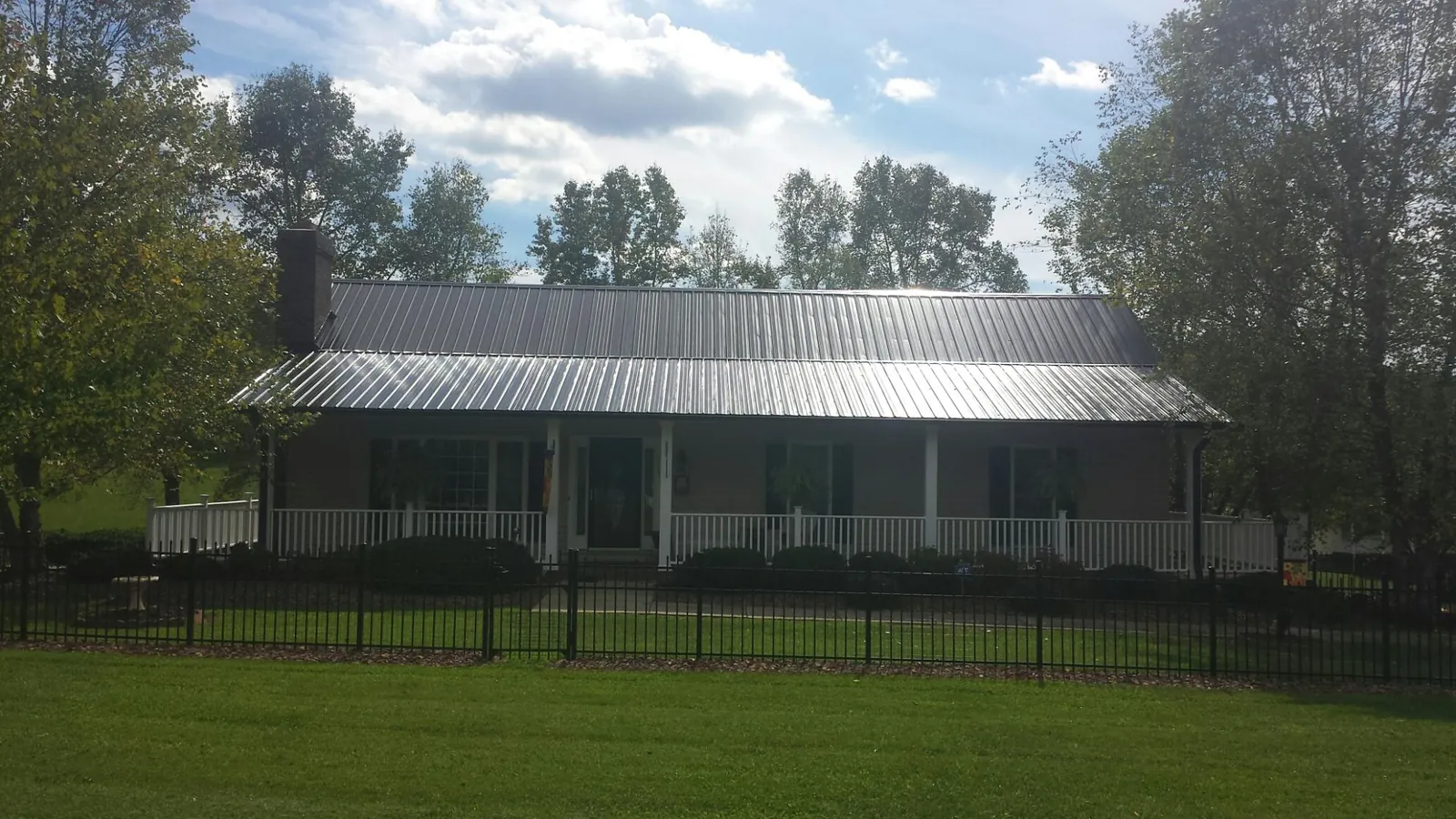Gray metal roof on a brick ranch with a full width front porch — Gutter Guard Installation work by our crew in Trivoli