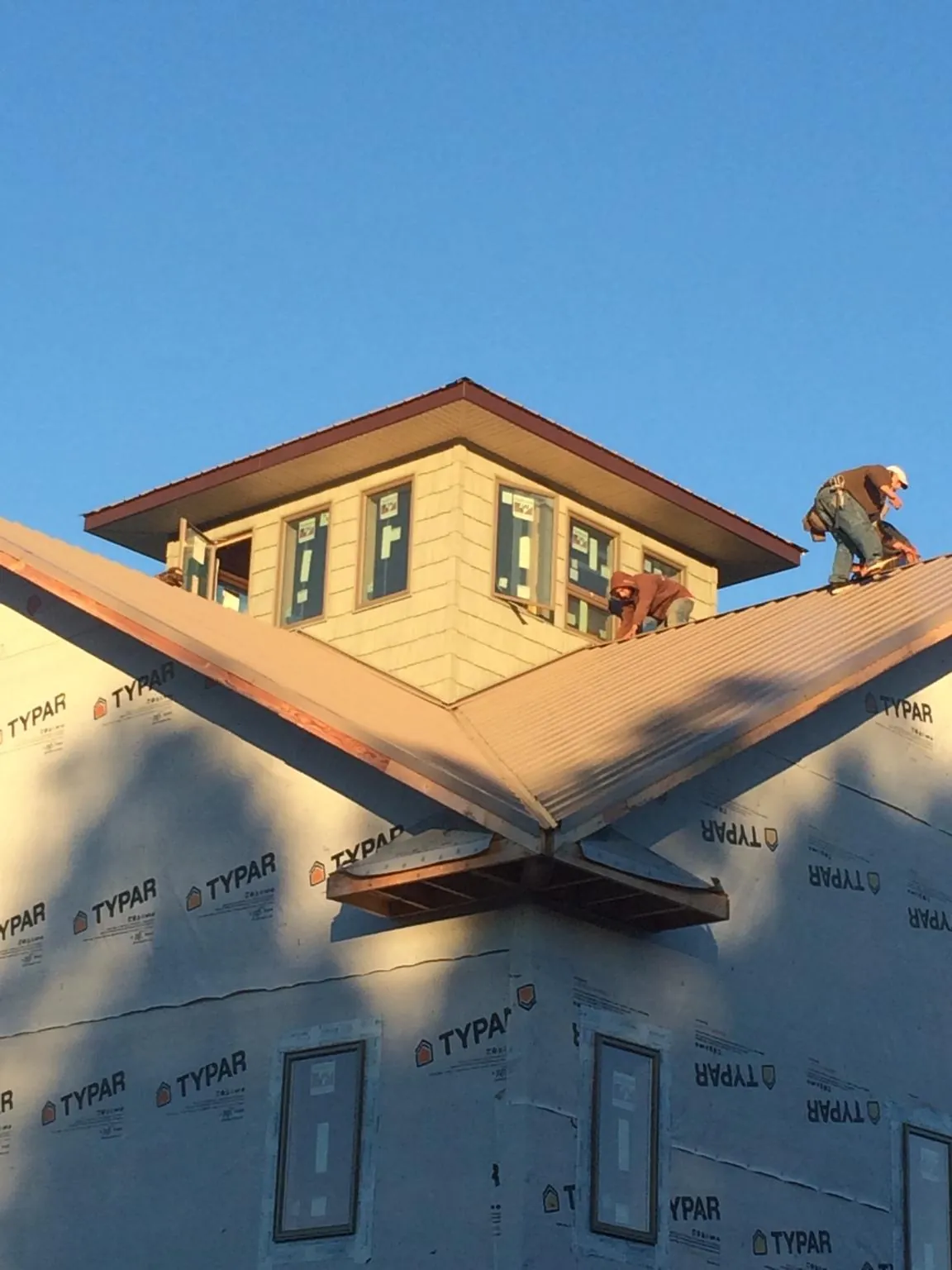 Roofers working around a rooftop cupola on a new metal roof at sunset — Roof Waterproofing in Trivoli by Roofing Brothers